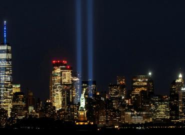 The New York city skyline including the Statue of liberty lit up at night. 