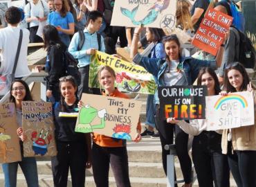 students gather holding climate protest signs