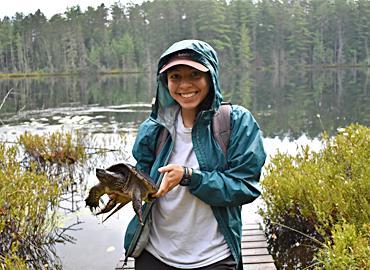 Mariel Terebiznik holds a juvenile snapping turtle in the field. The U of T alum is a co-founder of the FREED program. Photo credit: Jasmine Veitch.